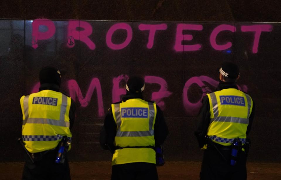 Police officers stand in front of a branch of Santander on St Vincent Street, Glasgow, where graffiti has been sprayed on the wall, as Extinction Rebellion protest outside. (PA)