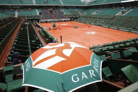 Spectators protect themselves from the rain with an umbrella on the Philippe Chatrier court during a delay as they follow the women's singles match between Ekaterina Makarova of Russia and Ana Ivanovic of Serbia at the French Open tennis tournament at the Roland Garros stadium in Paris, France, May 31, 2015. REUTERS/Jean-Paul Pelissier