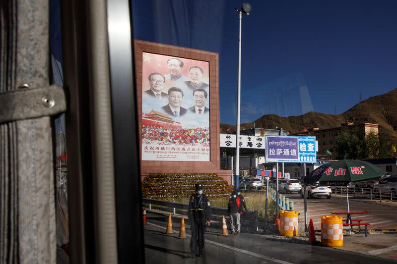 A bus carrying foreign journalists on a government tour passes portraits of Chinese President Xin Jinping and former leaders at a checkpoint in Lhasa