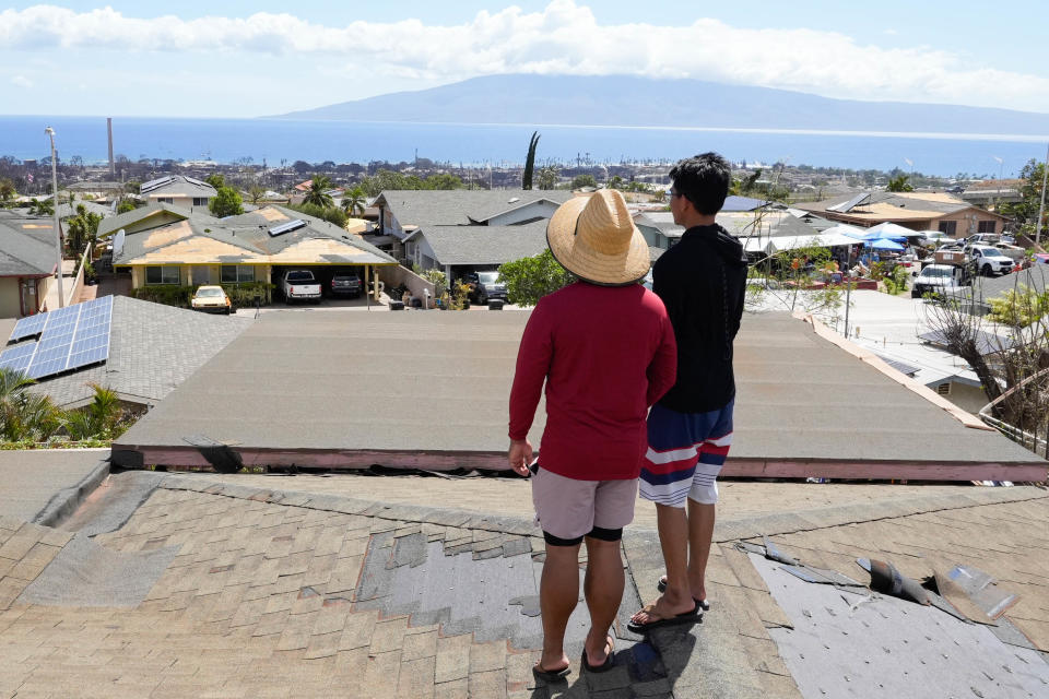 Nelson Simpliciano, left, and Addison Simpliciano stand on their roof overlooking Lahaina. Rooftops in the Lahainaluna neighborhood had their shingles ripped off due to 60 mph gusts from Hurricane Dora last week. The winds also fueled a wildfire that destroyed much of Lahaina.