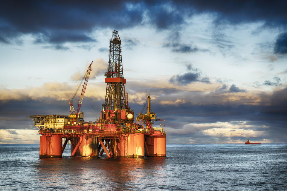 An offshore drilling rig in the ocean at dusk