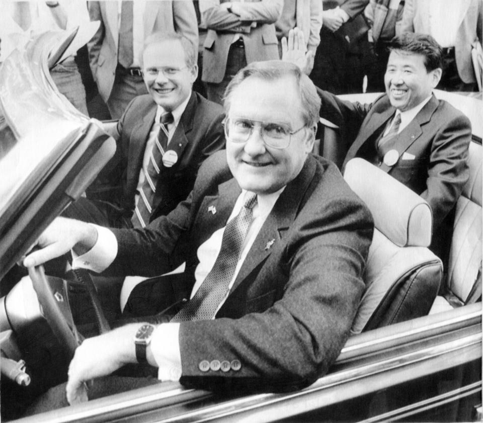 FILE - In this Oct. 7, 1985 file photo, Illinois Gov. James R. Thompson, behind the wheel of a Chrysler convertible, is joined by G. Glenn Gardner, left, and Yoichi Nakane, after a news conference in Chicago. Thompson, known as “Big Jim” during a long career that eventually made him the state's longest-serving chief executive, has died. He was 84. Thompson died Friday, Aug. 14, 2020 at the Shirley Ryan AbilityLab in Chicago, his wife, Jayne, told the Chicago Tribune and the Chicago Sun-Times. (AP Photo/Mark Elias, File)