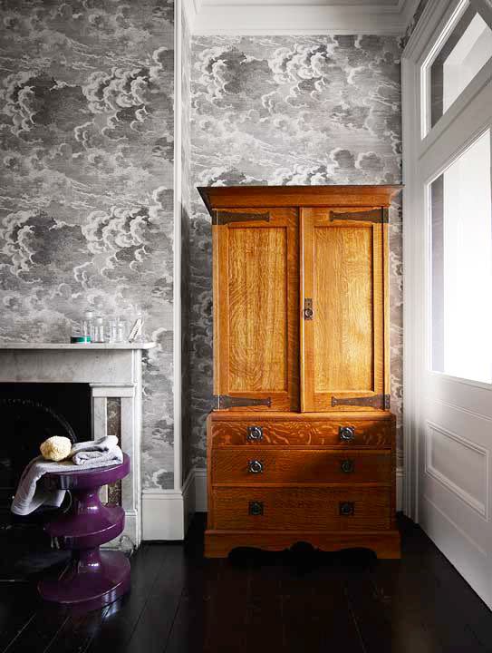 <p>If you don't want to install built-in shelves for whatever reason—renovation costs, rental limitations, or personal style—create more storage space with an armoire. This unexpected item is both traditional and quirky, especially when paired with Fornasetti's cloud-print wallpaper and a modern aubergine stool, as done in this bathroom decorated by Arent & Pyke. </p>