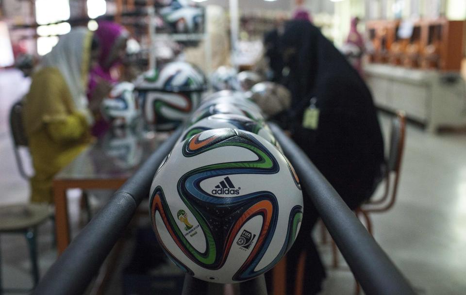 Employees work near official 2014 World Cup balls inside the soccer ball factory that produces official match balls for the World Cup in Brazil, in Sialkot, Punjab province