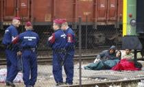 Hungarian police officers stand next to migrants at the Bicske railway station in Bicske, Hungary, September 4, 2015. REUTERS/Leonhard Foeger