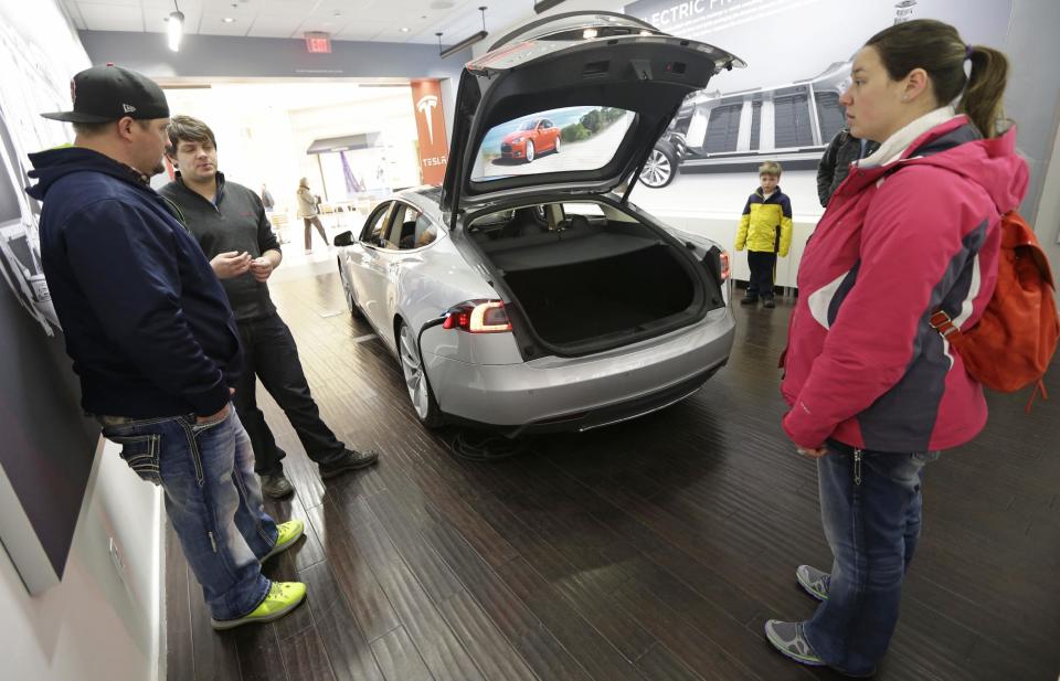 Robert Reynolds, left, and his wife Sarah, right, are shown a new Tesla all electric car by Tesla representative John Van Cleave, Monday, March 17, 2014, at a Tesla showroom inside the Kenwood Towne Centre in Cincinnati. Ohio auto dealers are sparring at the Statehouse with the California-based Tesla, which is selling it's next generation electric cars from three Ohio storefronts. Lawmakers in Ohio and other states are trying to block Tesla direct sales on grounds they undercut traditional auto dealerships. (AP Photo/Al Behrman)