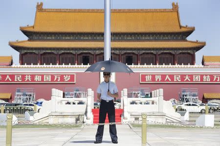 A paramilitary police officer in plain-clothes holding an umbrella keeps watch on Beijing's Tiananmen Square, August 27, 2015. REUTERS/Jason Lee