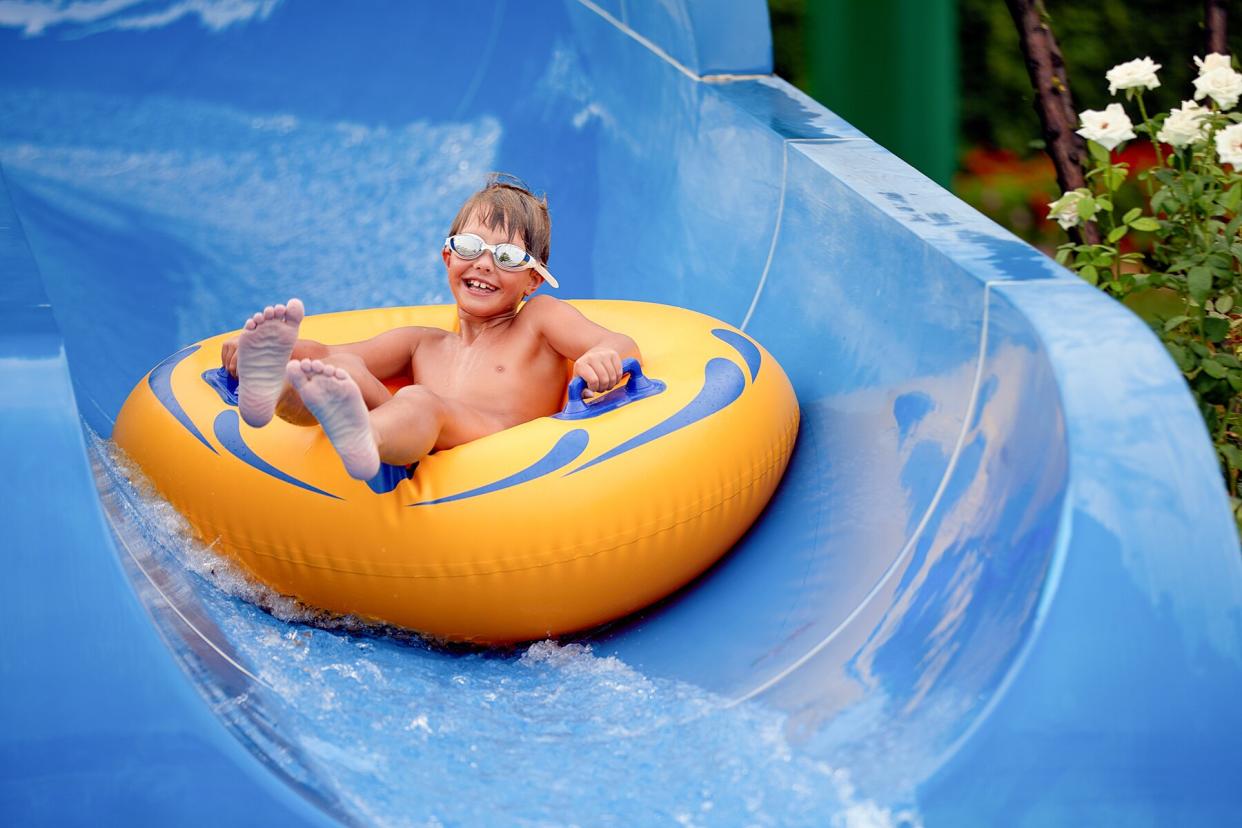 A Boy Sitting On an Inflatable Ring going down a waterslide