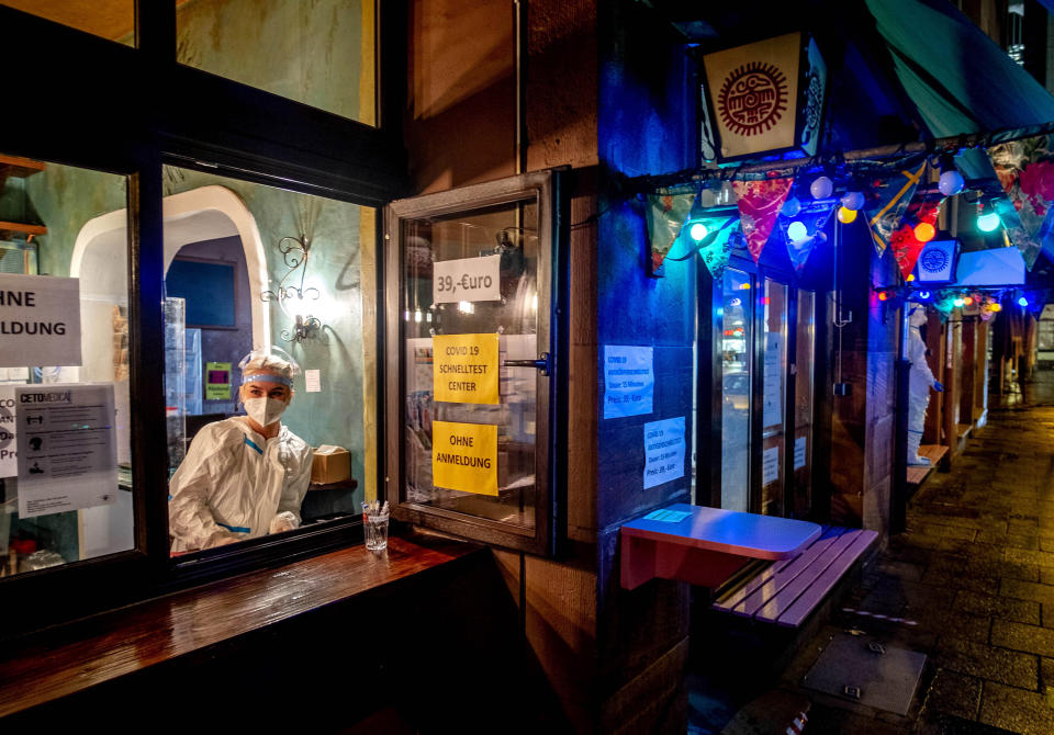 FILE - In this Dec. 15, 2020 file photo, a medical worker waits for customers at a corona quick test center that is located in an empty tequila bar in Frankfurt, Germany. More than 50,000 people have died after contracting COVID-19 in Germany, a number that has risen swiftly over recent weeks as the country has struggled to bring down infection figures. (AP Photo/Michael Probst, File)