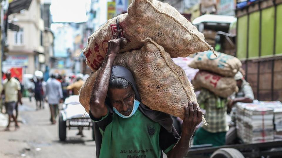 A worker carries sacks of onions in the Pettah area in Colombo