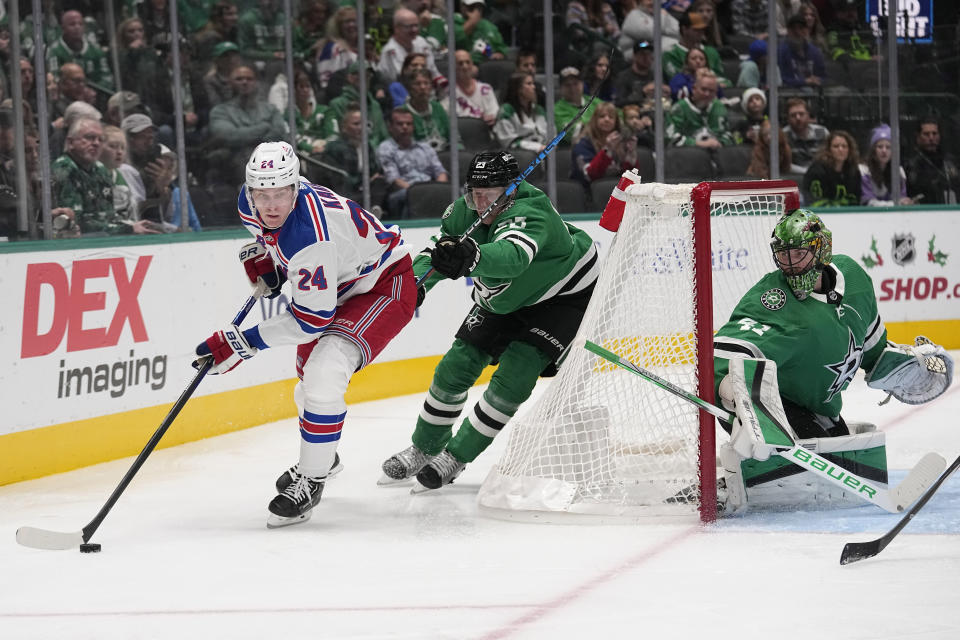 New York Rangers right wing Kaapo Kakko (24) looks to pass the puck as Dallas Stars' Esa Lindell (23) and goaltender Scott Wedgewood, right, defend the net in the second period of an NHL hockey game in Dallas, Monday, Nov. 20, 2023. (AP Photo/Tony Gutierrez)