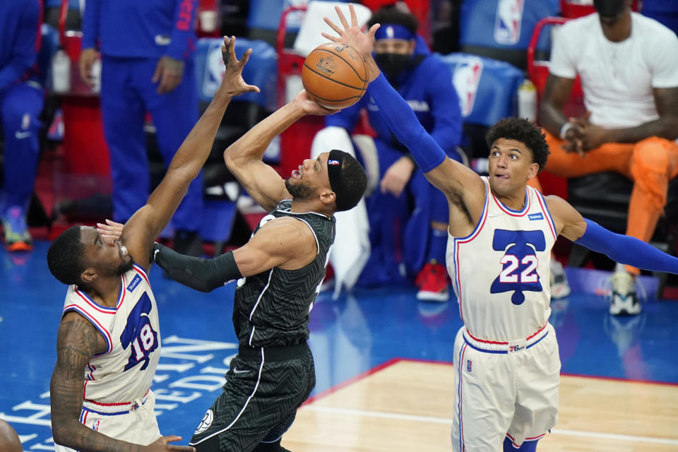 Brooklyn Nets' Bruce Brown, center, goes up for a shot against Philadelphia 76ers' Shake Milton, left, and Matisse Thybulle during the second half of an NBA basketball game, Wednesday, April 14, 2021, in Philadelphia. (AP Photo/Matt Slocum)