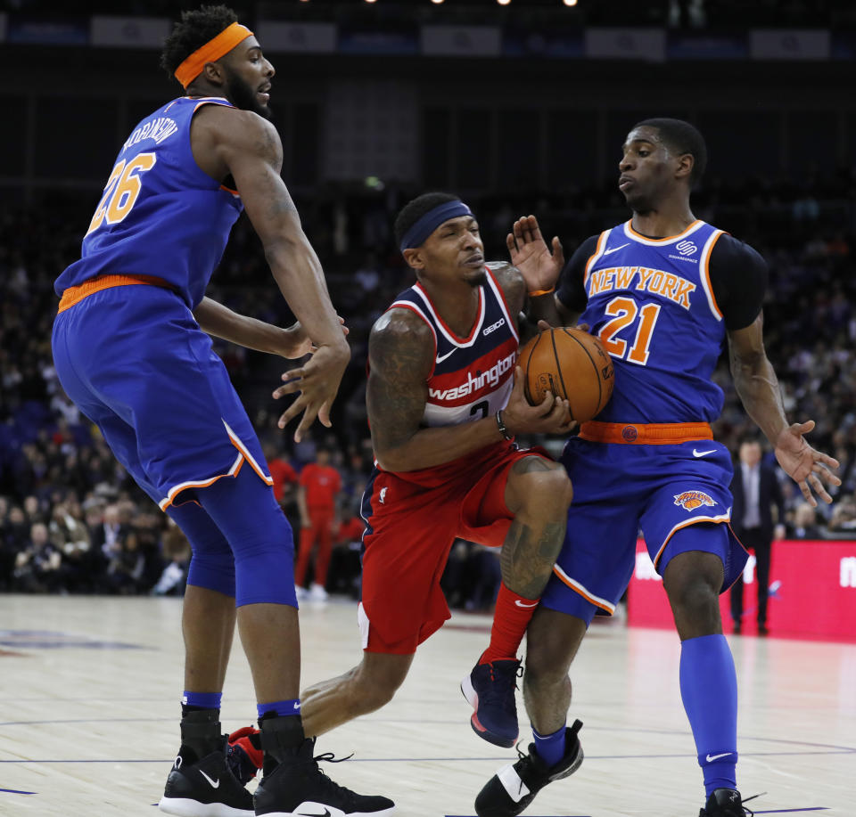 Washington Wizards guard Bradley Beal (3),center, drives to the basket flanked by New York Knicks center Mitchell Robinson (26), left, and his teammate guard Damyean Dotson (21), during an NBA basketball game between New York Knicks and Washington Wizards at the O2 Arena, in London, Thursday, Jan.17, 2019. (AP Photo/Alastair Grant)