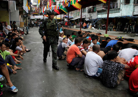People sit on a street after they were rounded up as they wait to be brought to a police station for verification if they are involved with drugs, after police sources and local media reported that people were killed during a raid, in Manila, Philippines, October 7, 2016. REUTERS/Czar Dancel/File Photo