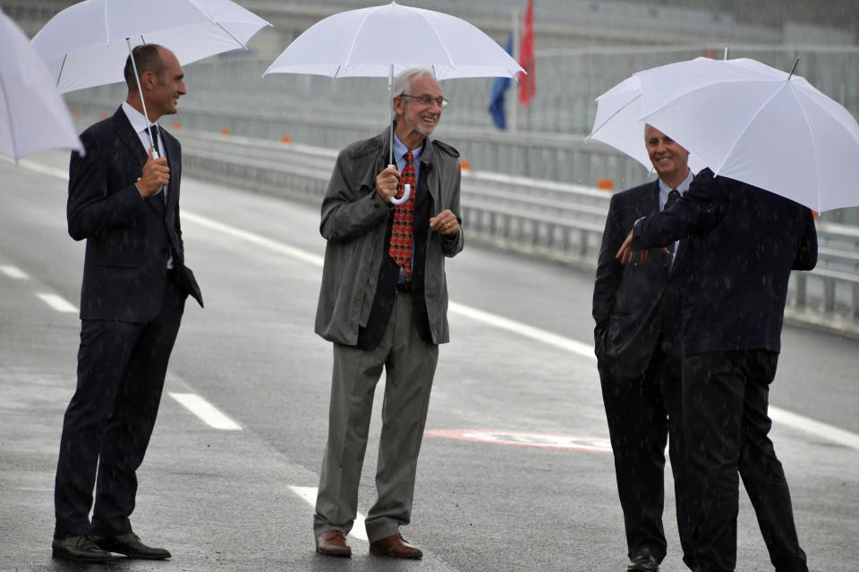 Renzo Piano, center, walks along the new San Giorgio Bridge in Genoa, Italy, Monday, Aug. 3, 2020. Two years ago this month, a stretch of roadbed collapsed on Genoa's Morandi Bridge, sending cars and trucks plunging to dry riverbed below and ending 43 lives. On Monday, Italy's president journeys to Genoa for a ceremony to inaugurate a replacement bridge. Designing the new span was Genoa native, Renzo Piano, a renowned architect. (Gian Mattia D'Alberto/LaPresse via AP)