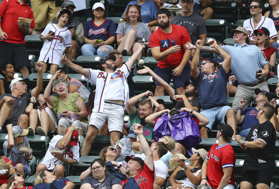 Atlanta Braves fans try to catch a foul ball while others duck to avoid being hit during the fourth inning of a baseball game against the Miami Marlins, Sunday, Sept. 4, 2022, in Atlanta. (Curtis Compton / Curtis Compton/Atlanta Journal-Constitution via AP)