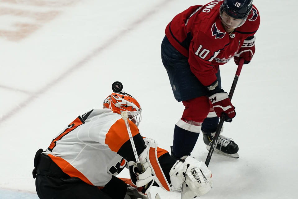 Washington Capitals right wing Daniel Sprong (10) watches the puck roll off the helmet of Philadelphia Flyers goaltender Brian Elliott (37) during the third period of an NHL hockey game, Friday, May 7, 2021, in Washington. The Flyers won 4-2. (AP Photo/Alex Brandon)