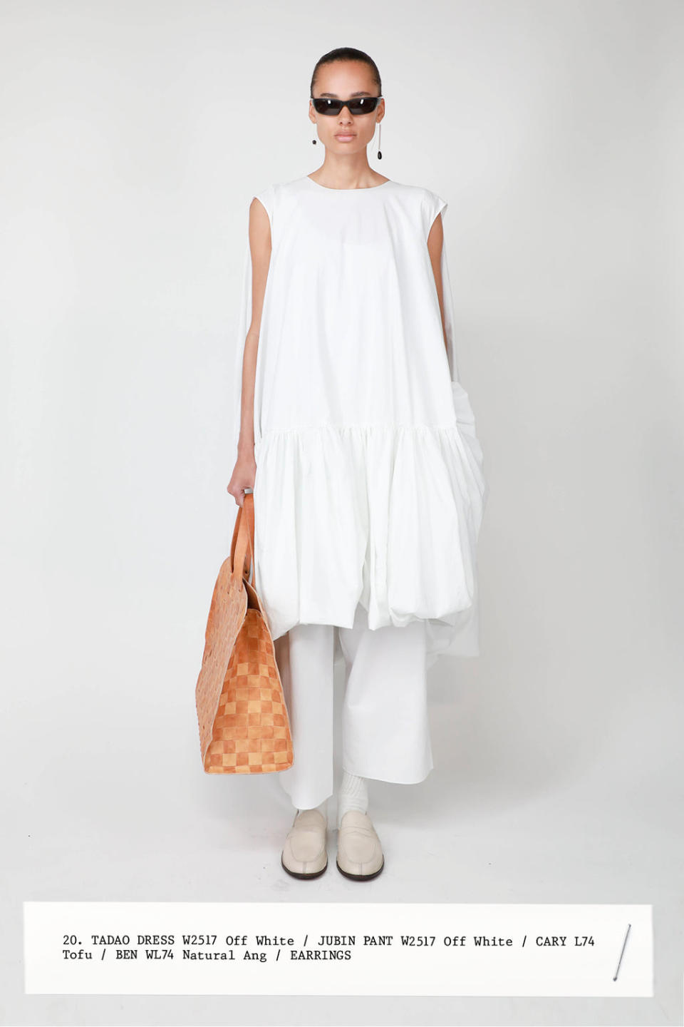 Model wearing a white dress, white pants, tote bag by The Row