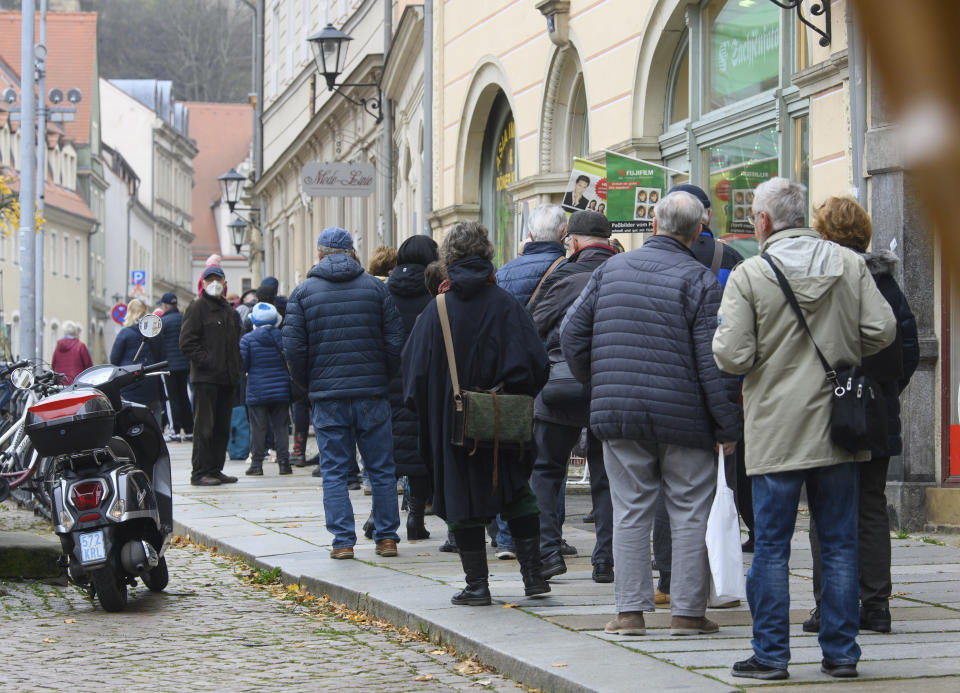 People wait in a long line to be vaccinated against the coronavirus during a vaccination campaign of the DRK, German Red Cross, in front of the town hall in Pirna, Germany, Monday, Nov. 15, 2021. (Robert Michael/dpa via AP)