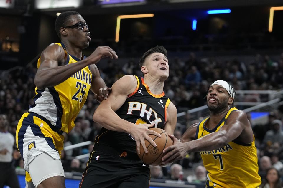 Phoenix Suns' Grayson Allen (8) goes to the basket against Indiana Pacers' Jalen Smith (25) and Buddy Hield (7) during the first half of an NBA basketball game Friday, Jan. 26, 2024, in Indianapolis. (AP Photo/Darron Cummings)
