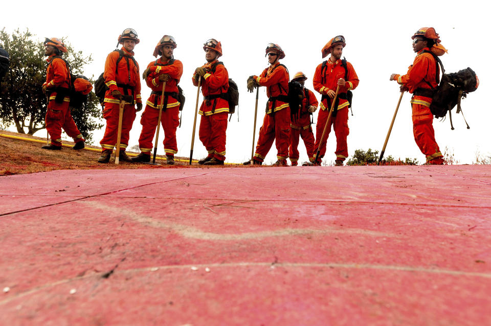 FILE - In this Aug. 17, 2020, photo, inmate firefighters - notable by their bright orange fire gear compared to the yellow worn by professional firefighters - prepare to take on the River Fire in Salinas, Calif. The California Senate on Thursday, June 23, 2022, rejected a proposal to ban involuntary servitude as punishment for a crime after Gov. Gavin Newsom's administration warned it could cost taxpayers billions of dollars by forcing the state to pay inmates who work while in prison a $15-per-hour minimum wage. (AP Photo/Noah Berger, File)