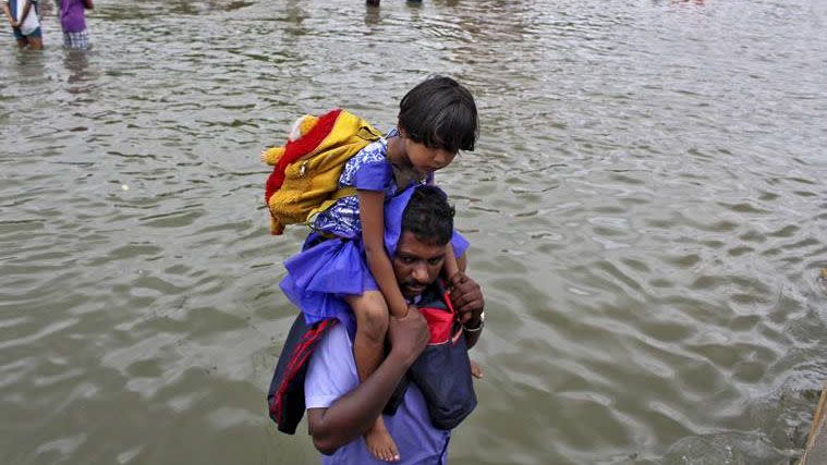 A man holds his child on his shoulders as he makes his way through floodwaters. Photo: Reuters