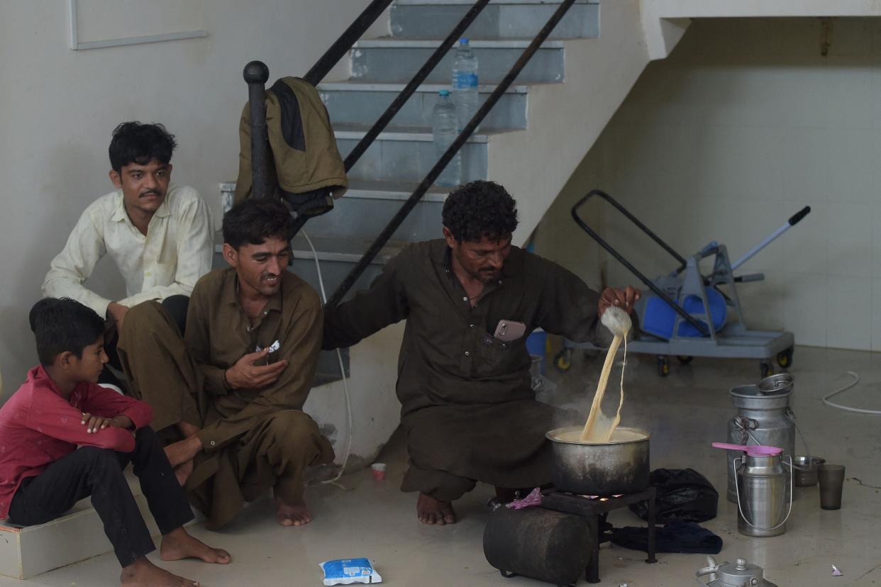 Residents make tea in a temporary shelter set at a primary health centre in Jakhau village of Kutch district in Gujarat state ahead of cyclone Biparjoy landfal (AFP via Getty Images)