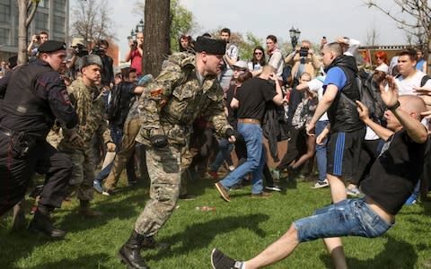 A fighter of National Liberation Movement pushes a protester down, during clashes at a demonstration against President Vladimir Putin - Credit: AP