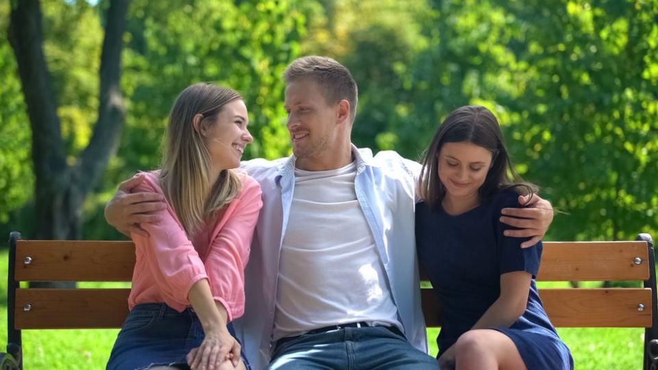 Throuple sitting together on a bench