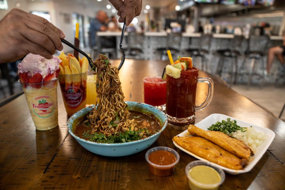 Gamaliel Garfio lifts noodles from a birria ramen plate at Frutilandia and Taqueria Factory in Tempe on Jan. 12, 2024.