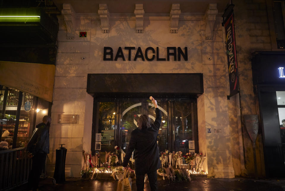 PARIS, FRANCE - NOVEMBER 13: A Parisian holds a flower towards the Bataclan concert hall on the sixth anniversary of the 13th November 2015 Paris terror attacks on November 13, 2021 in Paris, France. In November 2015, three teams of jihadists launched an attack consisting of suicide bombings and gun assaults on bars, restaurants and the Bataclan concert hall, killing 130 people, for which the Islamic State claimed responsibility. The trial over these attacks is currently ongoing. (Photo by Kiran Ridley/Getty Images)