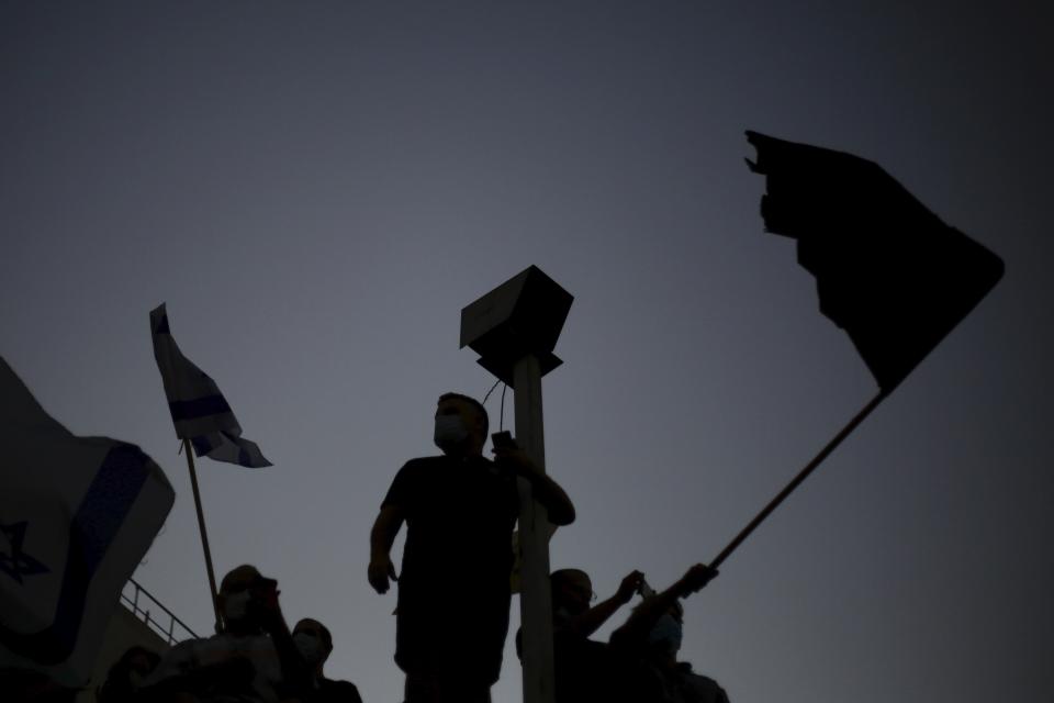 Protesters wave flags outside of the Prime Minister's residence in Jerusalem, Tuesday, July 14, 2020. Thousands of Israelis on Tuesday demonstrated outside the official residence of Prime Minister Benjamin Netanyahu, calling on the embattled Israeli leader to resign as he faces a trial on corruption charges and grapples with a deepening coronavirus crisis. (AP Photo/Ariel Schalit)