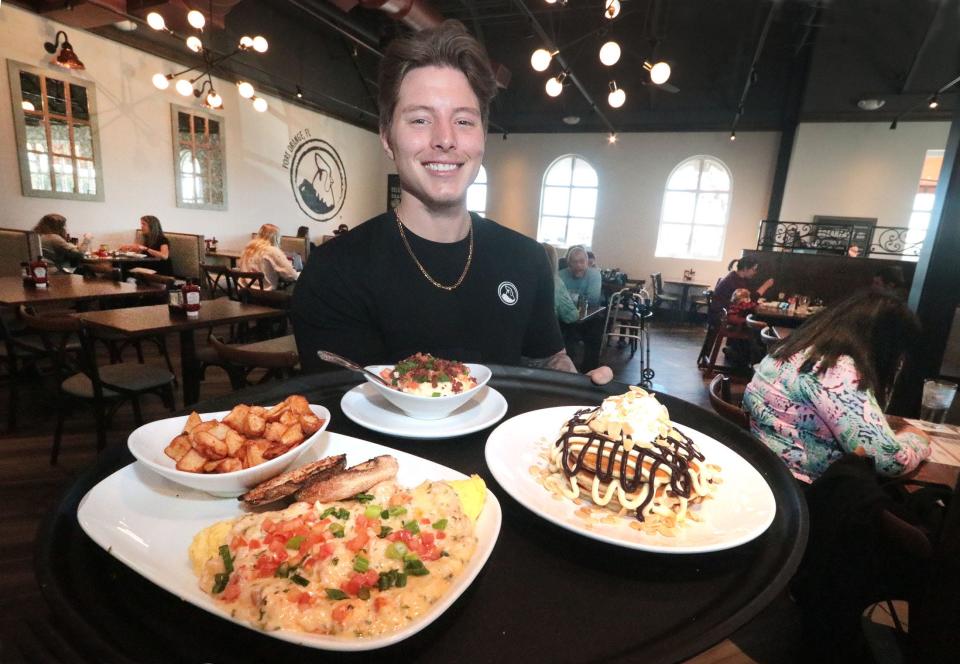 Server Logan Hamilton with a lobster and brie omelet, City Grits and Boston cream pancakes, Tuesday, Jan. 18, 2021, at Another Broken Egg Café at the Pavilion in Port Orange. “The food is incredible,” general manager Tim Wood said. “We celebrate indulgence, and we try to present the ‘wow’ factor.”