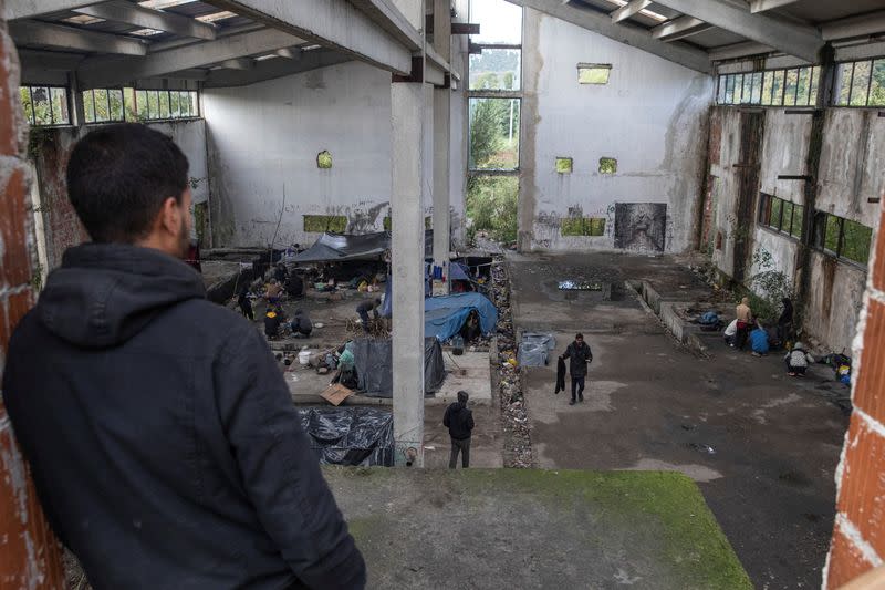 Migrants from Bangladesh stand inside an old abandoned factory near Velika Kladusa