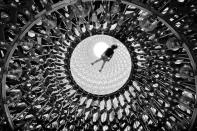 <p>Kew Gardens’ ‘Hive’ installation is seen from below, as a visitor lies on the top glass platform. (Naf Selmani) </p>