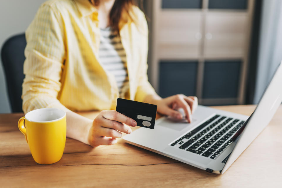 Shot of pretty young woman shopping online with credit card and laptop while sitting on the floor at home.