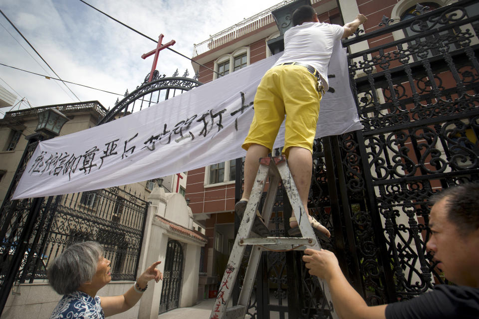 FILE - Church members put up a banner reading "Safeguard the dignity of belief, oppose the forcible removal of crosses" at the entrance of the Jingda Catholic Church in Jingda Village in Yongjia County in eastern China's Zhejiang Province on July 30, 2015. Chinese President Xi Jinping's first trip overseas since the early days of the COVID-19 pandemic will overlap with a visit by Pope Francis to Kazakhstan, although the Vatican says there are no plans for them to meet. Under Xi, China has launched a crackdown on Christianity in recent years, part of an overall tightening on religious freedoms which has affected worshippers of Islam, Christianity, and to a lesser extent, Buddhism and Daoism. (AP Photo/Mark Schiefelbein, File)