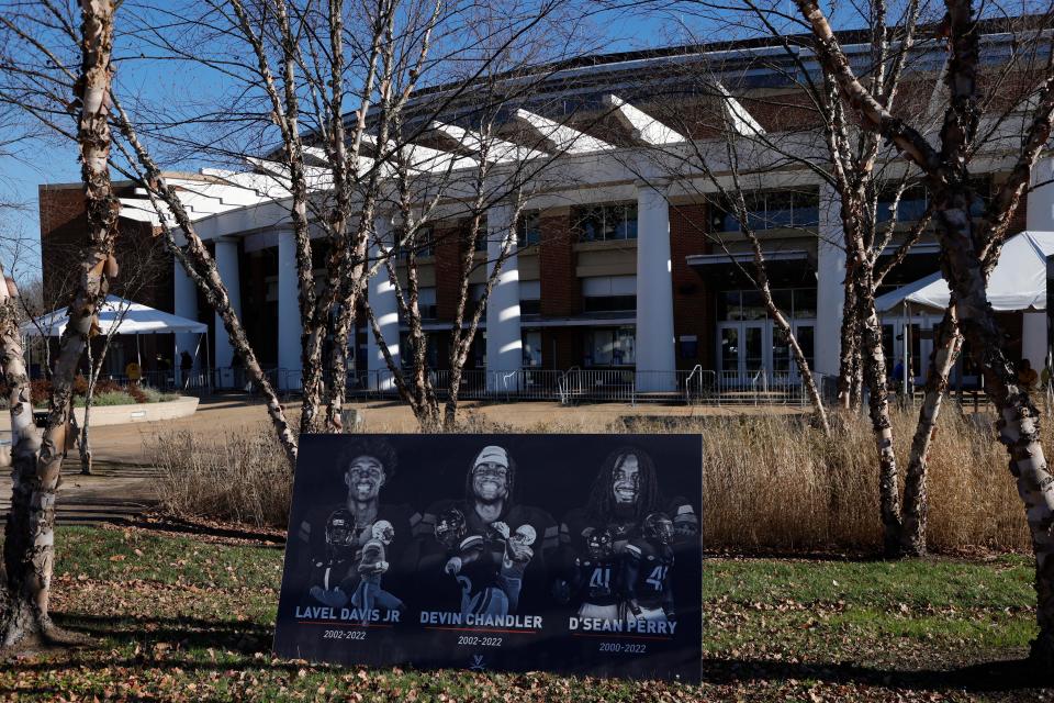 A board with a picture of each of the three Virginia Cavaliers football players killed in a campus shooting on Nov. 13, 2022, is displayed prior to the start of a memorial at John Paul Jones Arena.