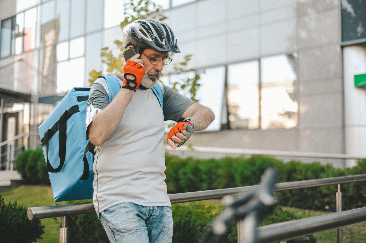 Delivery man wearing cycling helmet and backpack going to his next customer