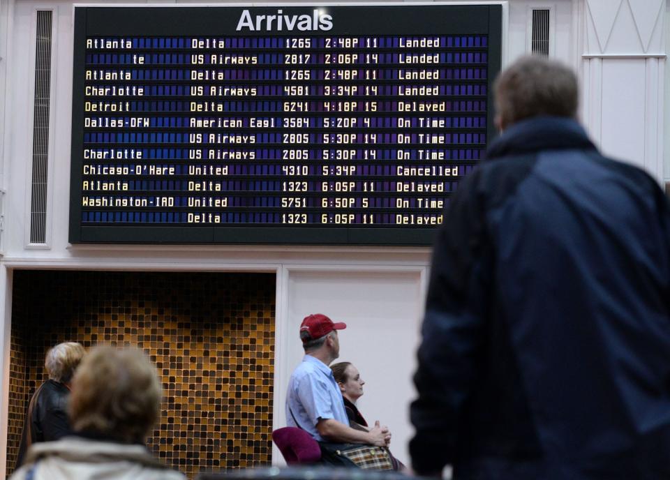 People awaiting arrivals at Savannah/Hilton Head International Airport look at the board as a few flights are marked as delayed or canceled due to weather issues in the northeast.