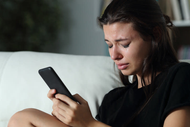 Woman looking sad and holding her phone