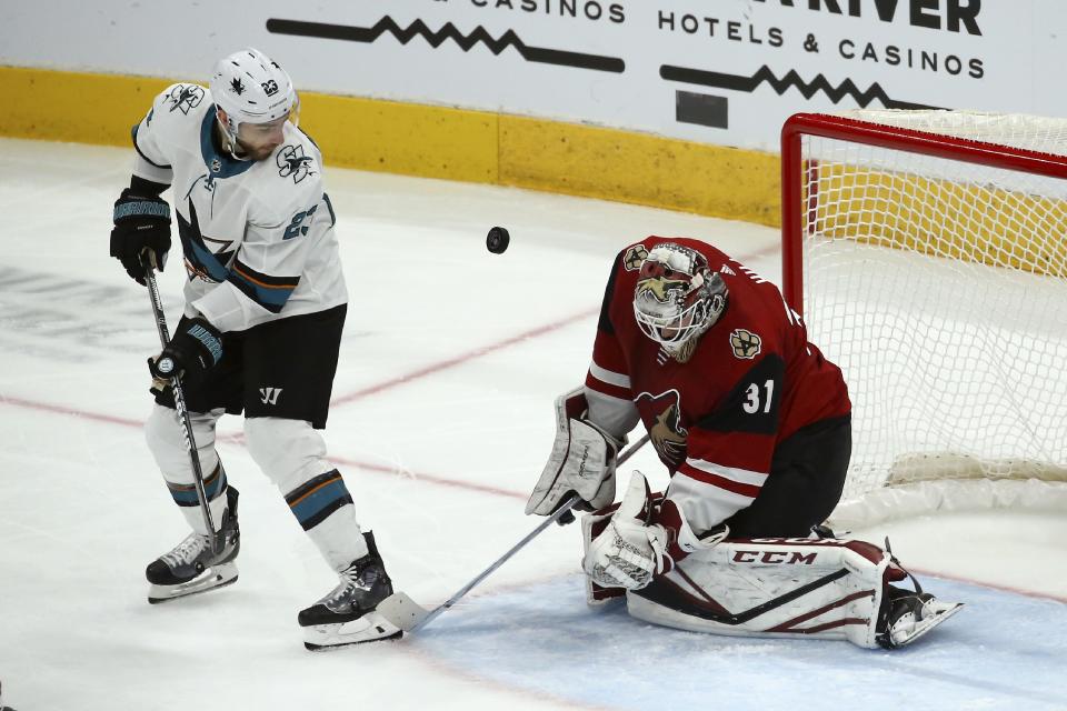 Arizona Coyotes goaltender Adin Hill (31) makes a save on a shot as San Jose Sharks right wing Barclay Goodrow (23) looks on during the second period of an NHL hockey game Tuesday, Jan. 14, 2020, in Glendale, Ariz. (AP Photo/Ross D. Franklin)