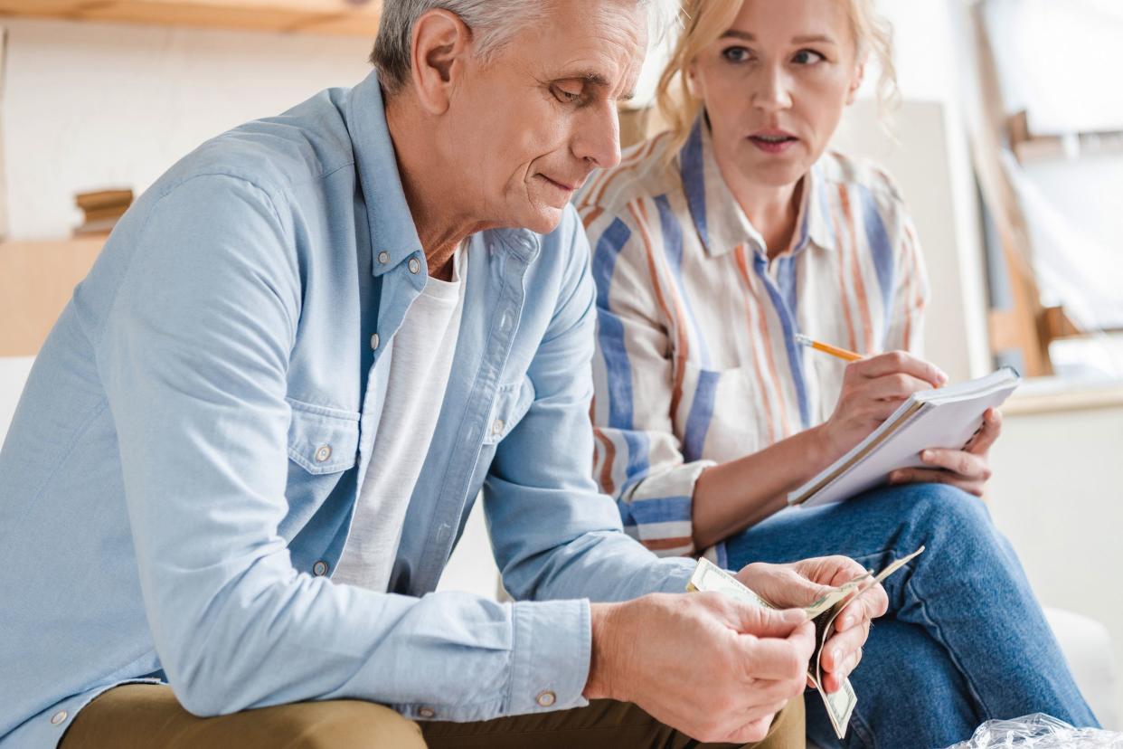 serious senior couple counting money and taking notes during relocation