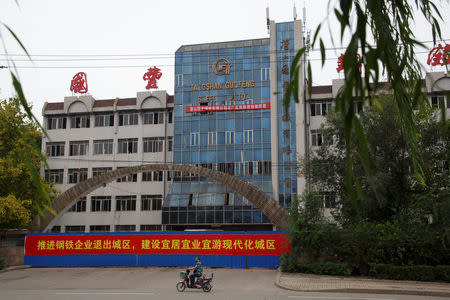 A man rides a scooter past the former office building of the decommissioned Guofeng Iron and Steel plant in Tangshan, Hebei province, China, August 22, 2018. REUTERS/Thomas Peter