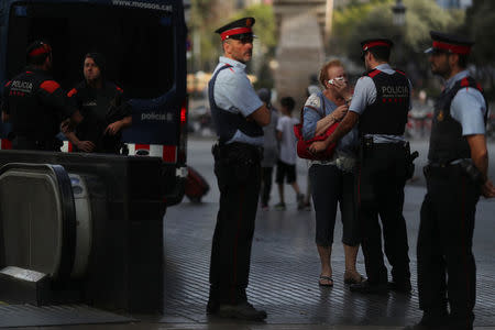 Pilar Revilla, 75, gets emotional after hugging a Catalan Mossos d'Esquadra officer after visiting an impromptu memorial where a van crashed into pedestrians at Las Ramblas in Barcelona, Spain, August 20, 2017. REUTERS/Susana Vera