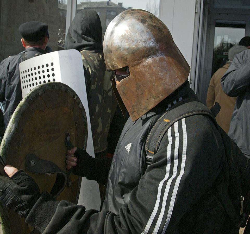 An activist in a handmade metallic helmet stands behind a barricade at the regional administration building in Donetsk, Ukraine, Monday, April 7, 2014. Outside the Donetsk building, a barricade of car tires and razor wire was built up to thwart police from retaking it. Interfax cited police in Donetsk as saying one armed group fired into the air and attempted to seize the regional state television broadcaster Monday but retreated after police and guards in the building also fired warning shots into the air. (AP Photo/Alexander Ermochenko)