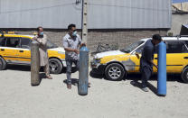 Men carry cylinders to refilled from a privately owned oxygen factory, in Kabul, Afghanistan, Saturday, June 19, 2021. Health officials say Afghanistan is fast running out of oxygen as a deadly third surge of COVID worsen. (AP Photo/Rahmat Gul)