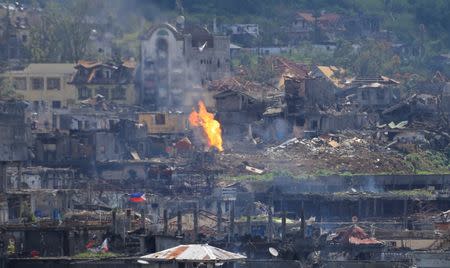 Flame rises as damaged buildings are seen after government troops cleared the area from pro-Islamic State militant groups inside a war-torn area in Marawi city, southern Philippines October 23, 2017. REUTERS/Romeo Ranoco