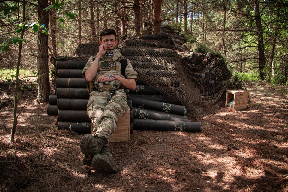 A Ukrainian soldier with the 57th Motorized Brigade rests on a pile of artillery shells to be used in firing on Russian positions (Getty Images)