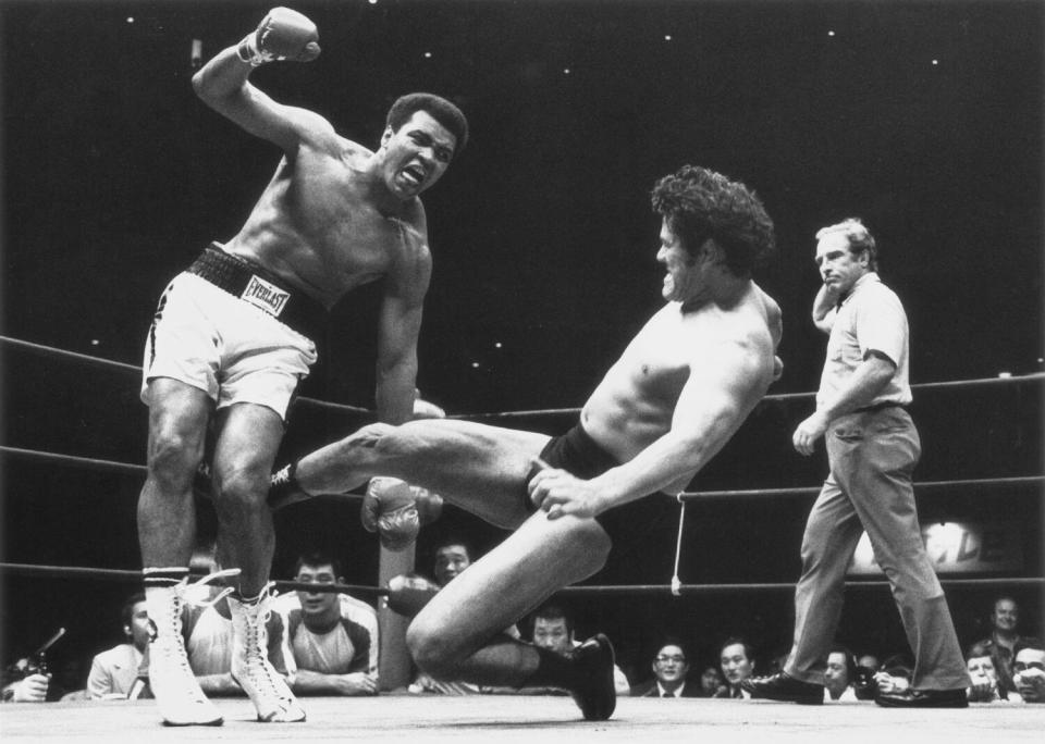 Japanese pro wrestler Antonio Inoki slide kicks the back of Muhammad Ali's leg during their boxing-wrestling bout.